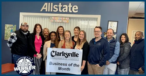 Group of people standing together indoors in front of a sign that says "Allstate" and a banner that reads "Clarksville Area Chamber of Commerce Business of the Month." They are smiling and posing for the photo, with some holding the sign.